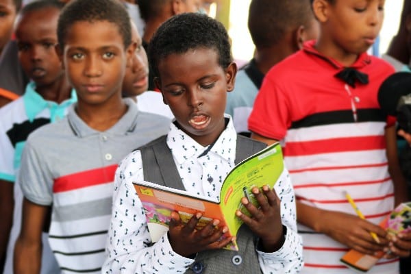 Un enfant tenant un cahier à l'envers 