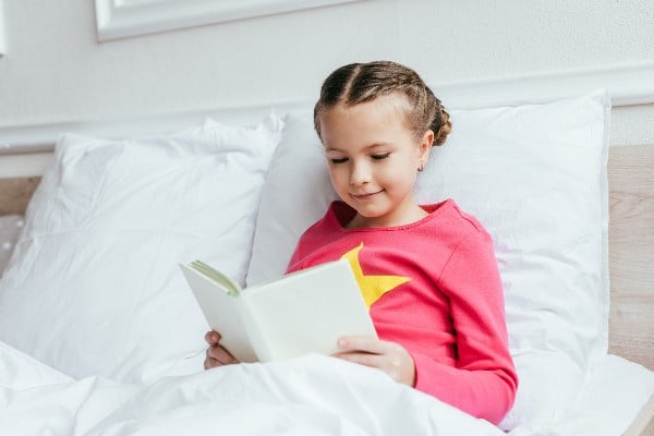 enfant souriant en lisant un livre